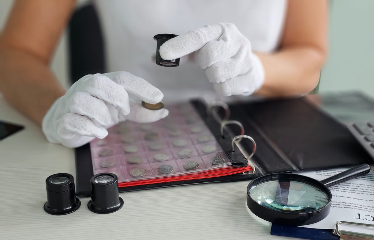 Examine vintage coins using magnifying glass and preservation tools